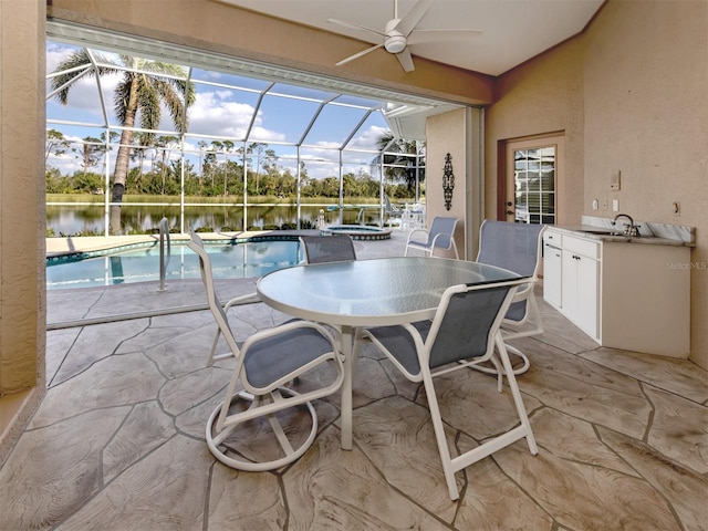 sunroom with a swimming pool, a sink, ceiling fan, and a water view