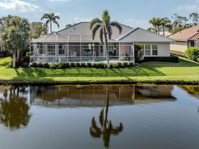 back of property with glass enclosure, a water view, and a tiled roof