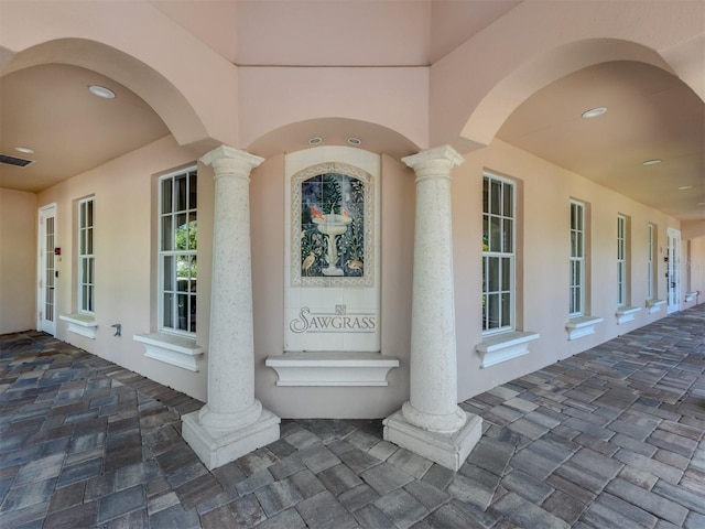 property entrance featuring stucco siding and visible vents