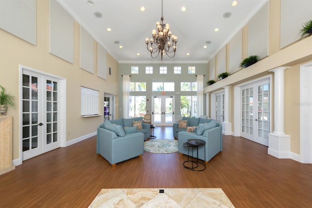 living room with french doors, crown molding, a towering ceiling, and wood finished floors