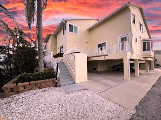 back of property featuring stairway, fence, driveway, and stucco siding