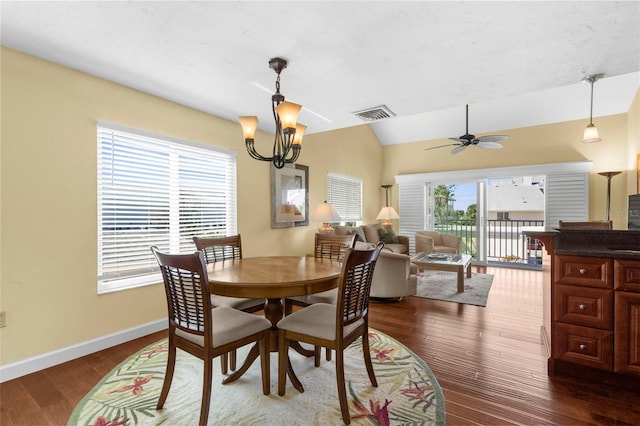 dining room with visible vents, dark wood-type flooring, baseboards, lofted ceiling, and ceiling fan with notable chandelier