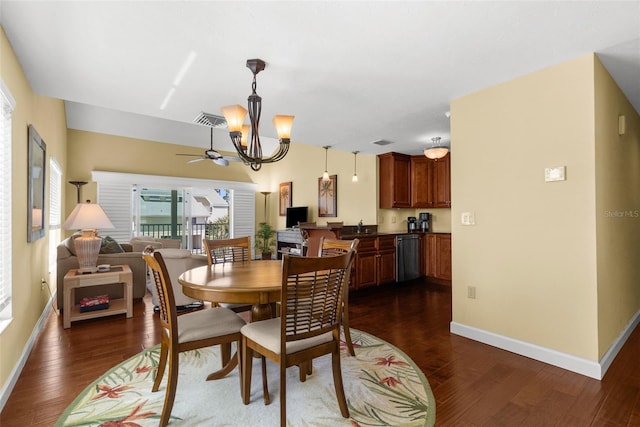 dining area featuring dark wood finished floors, ceiling fan with notable chandelier, visible vents, and baseboards