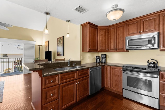 kitchen featuring visible vents, a sink, dark wood-style floors, a peninsula, and appliances with stainless steel finishes