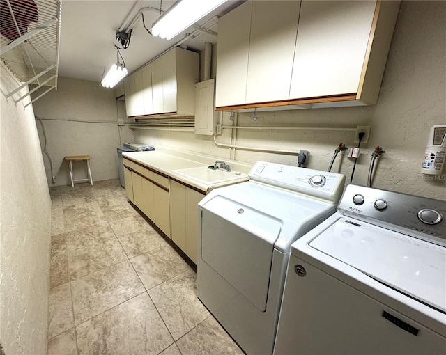 clothes washing area featuring light tile patterned floors, cabinet space, a sink, washer and dryer, and a textured wall