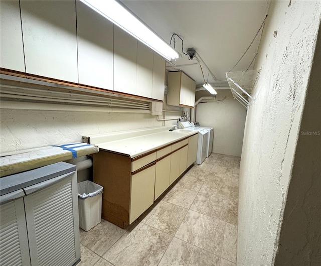 clothes washing area featuring light tile patterned floors, cabinet space, and a textured wall