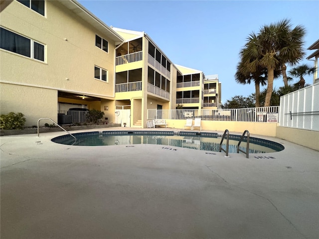 pool with a patio area and fence