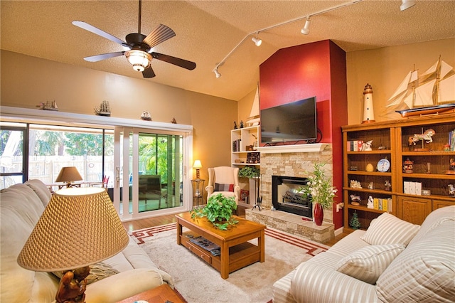 living room with lofted ceiling, a textured ceiling, a stone fireplace, and a ceiling fan