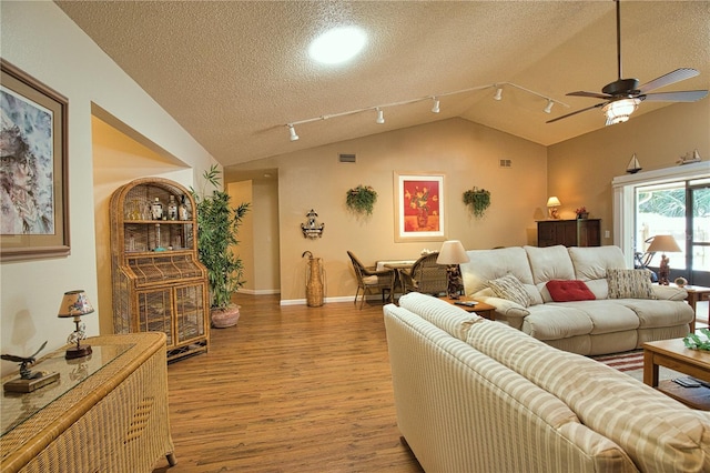 living area with visible vents, a ceiling fan, a textured ceiling, light wood-style floors, and vaulted ceiling