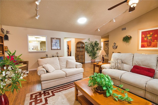 living area featuring visible vents, ceiling fan, vaulted ceiling, wood finished floors, and a textured ceiling