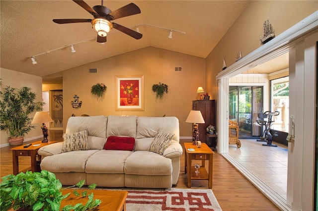 living room featuring light wood finished floors, visible vents, lofted ceiling, rail lighting, and a ceiling fan