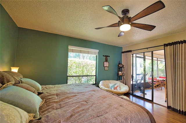 bedroom featuring multiple windows, wood finished floors, a ceiling fan, and access to outside