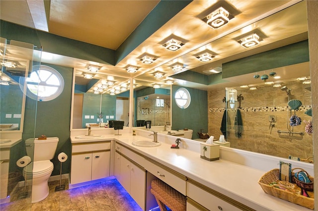 bathroom with toilet, tiled shower, vanity, and a tray ceiling