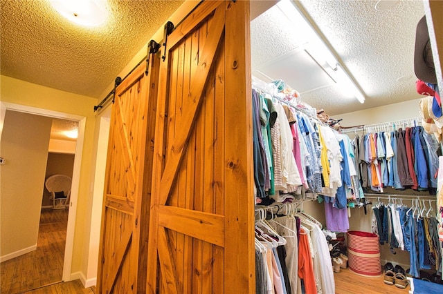 walk in closet featuring a barn door and wood finished floors