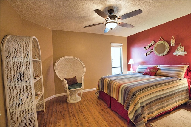 bedroom with baseboards, a textured ceiling, wood finished floors, and a ceiling fan