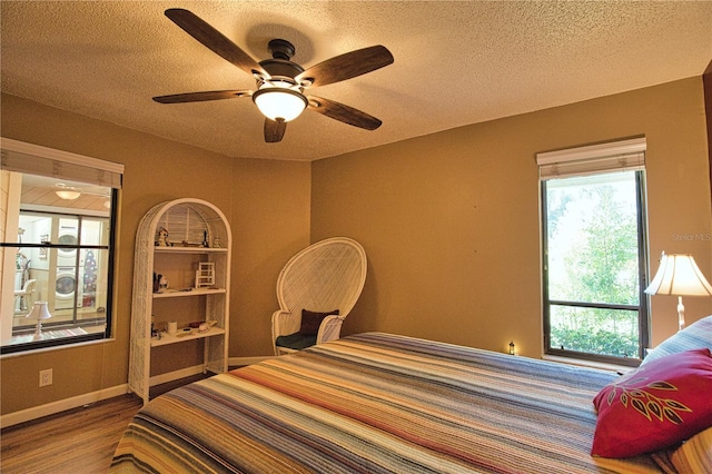 bedroom with baseboards, a textured ceiling, wood finished floors, and a ceiling fan