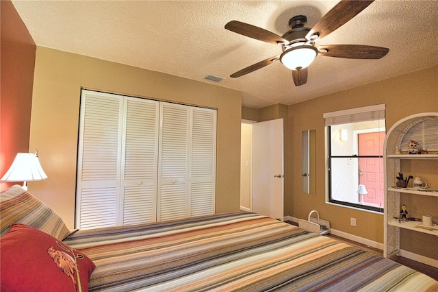 bedroom with a closet, visible vents, a textured ceiling, and baseboards