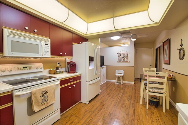 kitchen with red cabinetry, white appliances, light countertops, and light wood-style floors