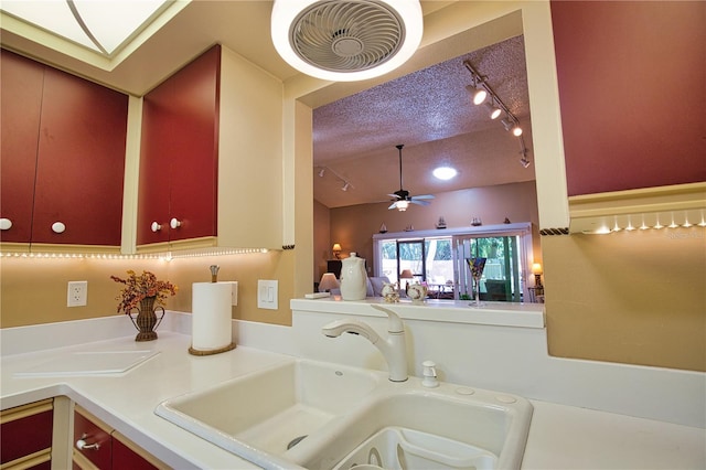 interior space featuring a ceiling fan, a sink, a textured ceiling, light countertops, and lofted ceiling