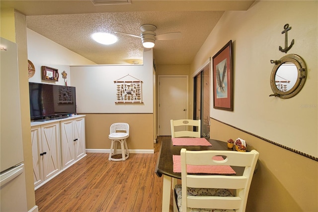 dining space featuring a textured ceiling, baseboards, and wood finished floors