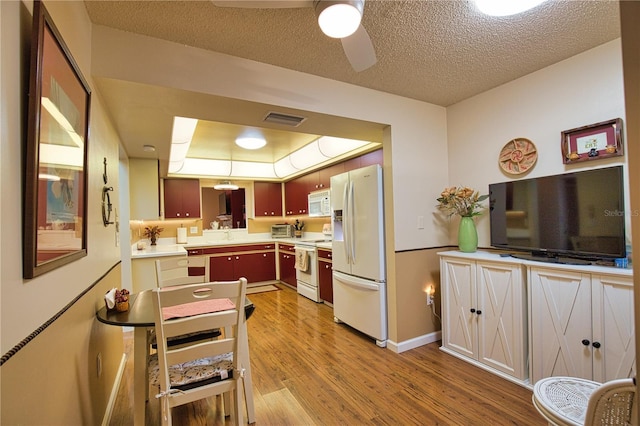 kitchen featuring visible vents, light countertops, light wood-style flooring, white appliances, and a ceiling fan