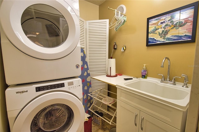 laundry area featuring a sink, cabinet space, and stacked washing maching and dryer