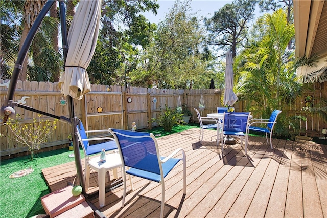 wooden terrace with outdoor dining area and a fenced backyard