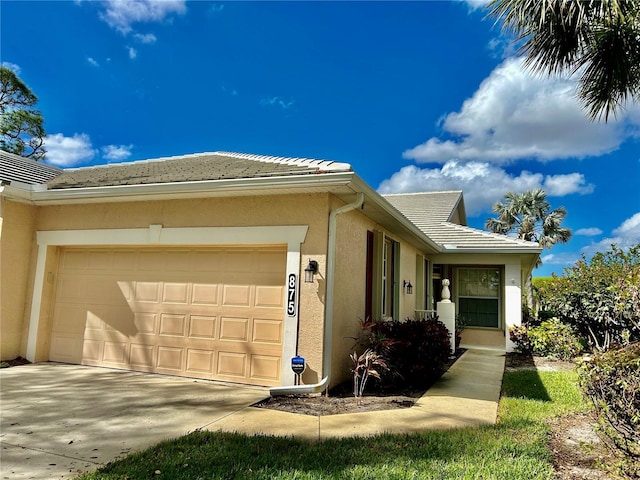 view of home's exterior with stucco siding, a garage, driveway, and a tile roof