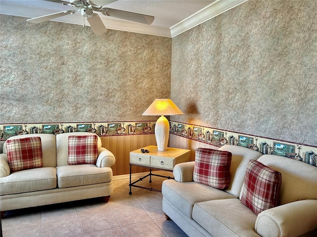 living area with ornamental molding, a ceiling fan, a textured ceiling, wallpapered walls, and tile patterned flooring