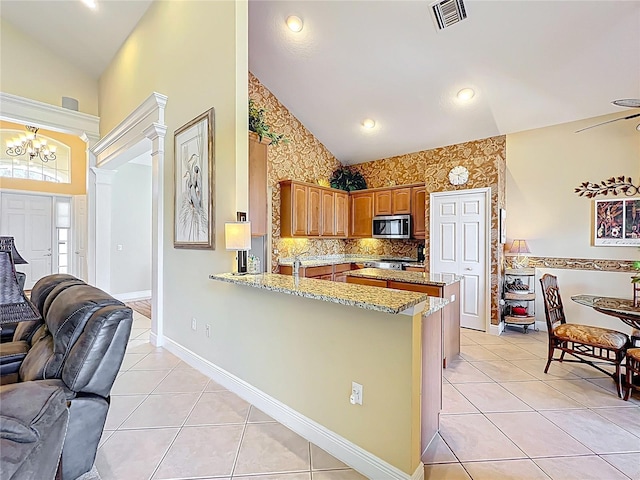 23901 Waverly Cir, Venice, FL 34293 - kitchen with stainless steel microwave, open floor plan, a peninsula, high vaulted ceiling, and light tile patterned flooring