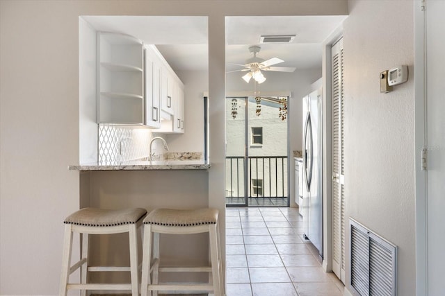 kitchen with visible vents, light tile patterned floors, freestanding refrigerator, white cabinetry, and open shelves