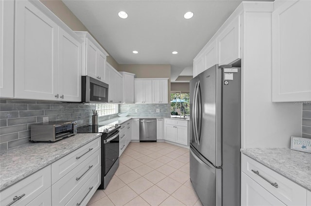 kitchen featuring light tile patterned flooring, stainless steel appliances, decorative backsplash, white cabinetry, and a wealth of natural light