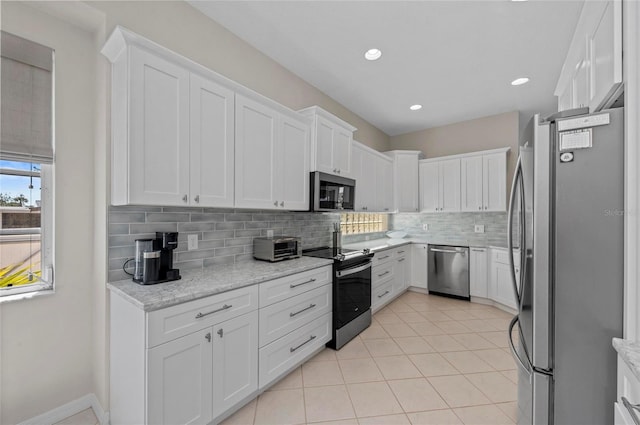 kitchen featuring backsplash, light tile patterned floors, light stone counters, appliances with stainless steel finishes, and white cabinets