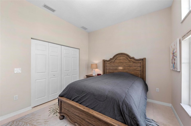 tiled bedroom featuring baseboards, visible vents, and a closet