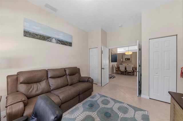 living area featuring light tile patterned floors, visible vents, and a towering ceiling