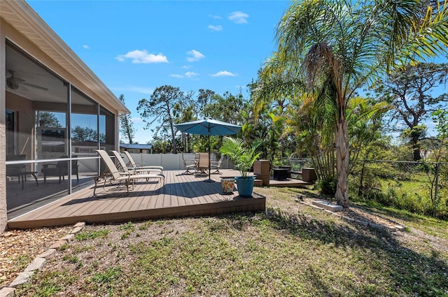 view of yard with a wooden deck, fence, ceiling fan, and a sunroom