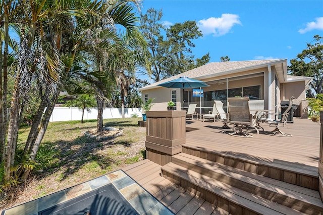 deck featuring outdoor dining area, a sunroom, and fence