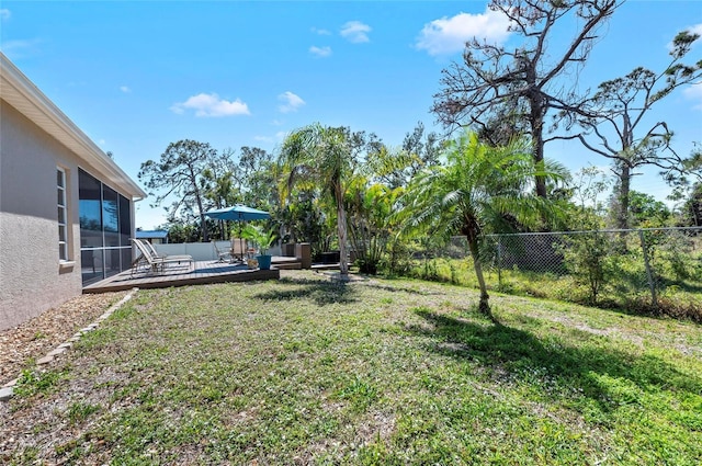 view of yard with a fenced backyard, a sunroom, and a wooden deck