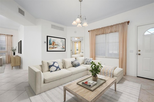 living area with light tile patterned flooring, visible vents, and an inviting chandelier