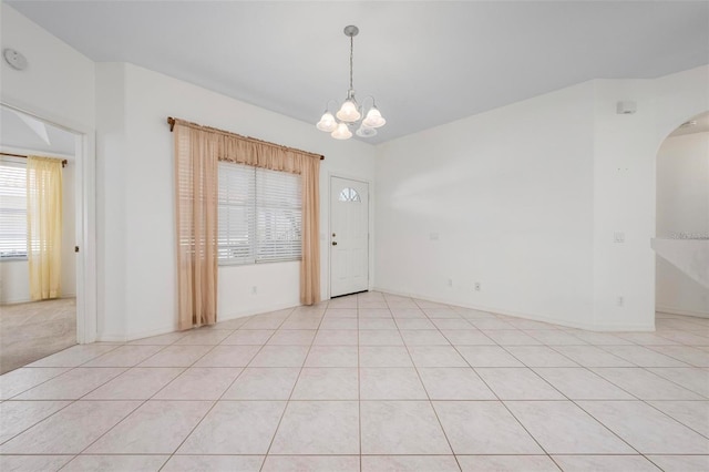 spare room with arched walkways and a chandelier