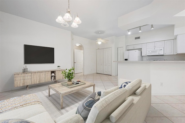 living area featuring visible vents, ceiling fan with notable chandelier, arched walkways, light tile patterned floors, and baseboards