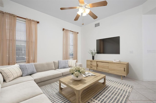 living room with light tile patterned floors, visible vents, baseboards, and a ceiling fan