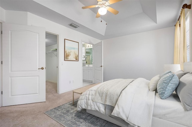 bedroom featuring visible vents, light carpet, connected bathroom, a raised ceiling, and a spacious closet