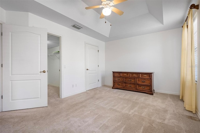 unfurnished bedroom with visible vents, a ceiling fan, carpet, a raised ceiling, and a spacious closet