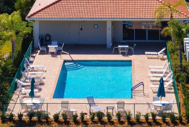 community pool with a patio and fence