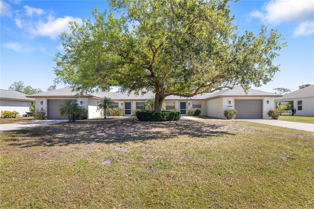 single story home featuring stucco siding, driveway, an attached garage, and a front yard