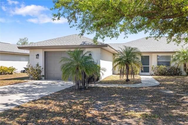 view of front facade with stucco siding, concrete driveway, a garage, and a shingled roof