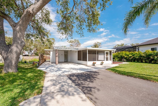 single story home with an attached carport, a front yard, fence, driveway, and a sunroom