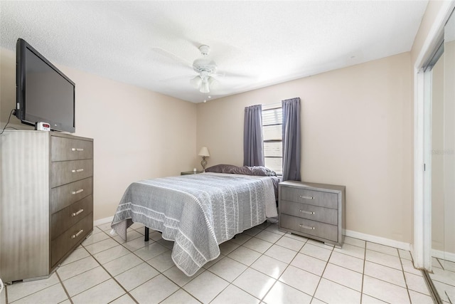 bedroom with light tile patterned floors, baseboards, a textured ceiling, and ceiling fan