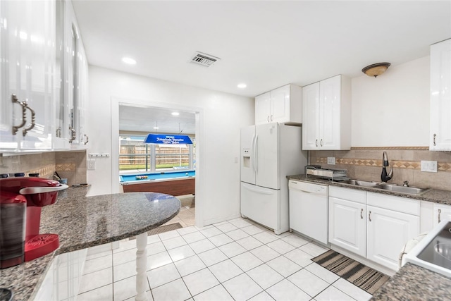 kitchen with tasteful backsplash, visible vents, white cabinets, white appliances, and a sink